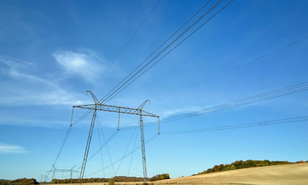 High voltage transmission power lines on steel towers carrying electricity across an open landscape