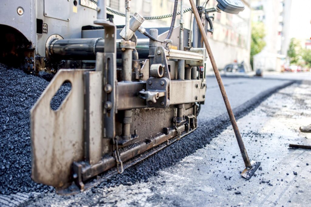 Asphalt paving machine laying fresh road surface during the asphalt road construction process with paving equipment and compacted materials